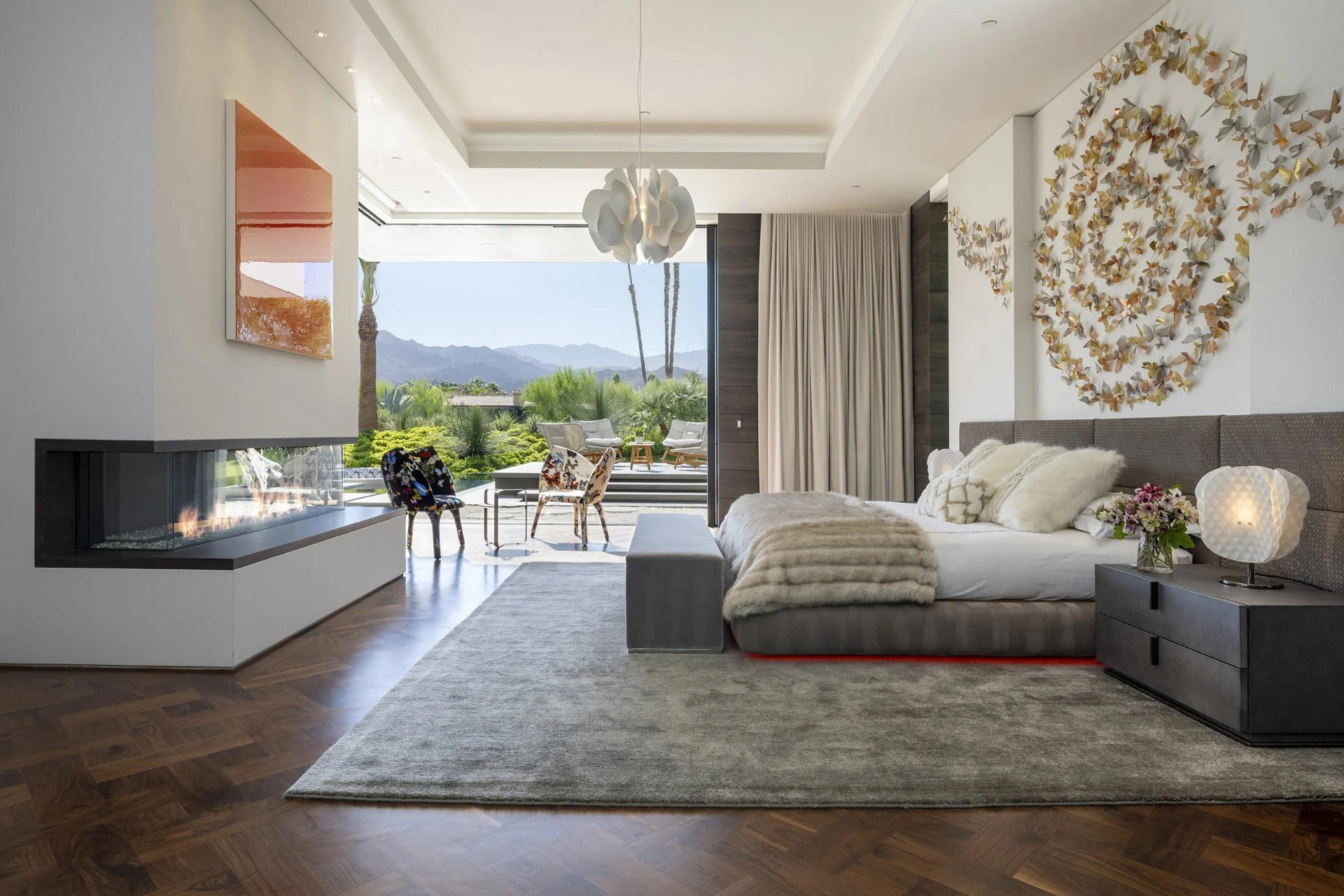 Spacious master suite with a fireplace, herringbone floors and garden views